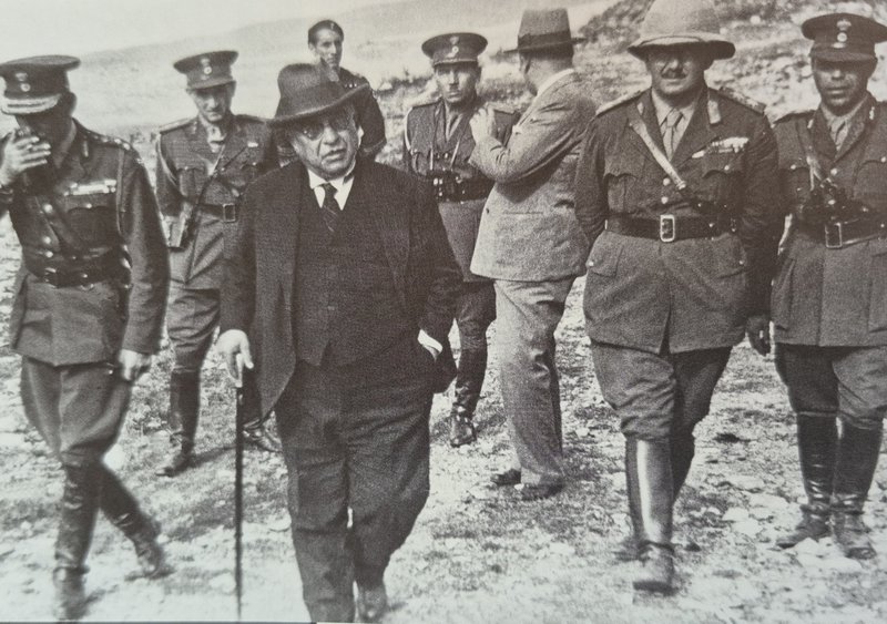 Ο Ιωάννης Μεταξάς επιθεωρεί έργα σε κάποιο οχυρό στην Ελληνοβουλγαρική μεθόριιο λίγους μήνες πριν την έναρξη του πολέμου, πλαισιωμένους από Έλληνες αξιωματικούς και ένα τοπικό πολιτικό αξιωματούχο. Ενδιαφέρον παρουσιάζει η παρουσία στα δεξιά ενός Βρετανού ανώτερου αξιωματικού που ξεχωρίζει από την αποικιακή στολή του.