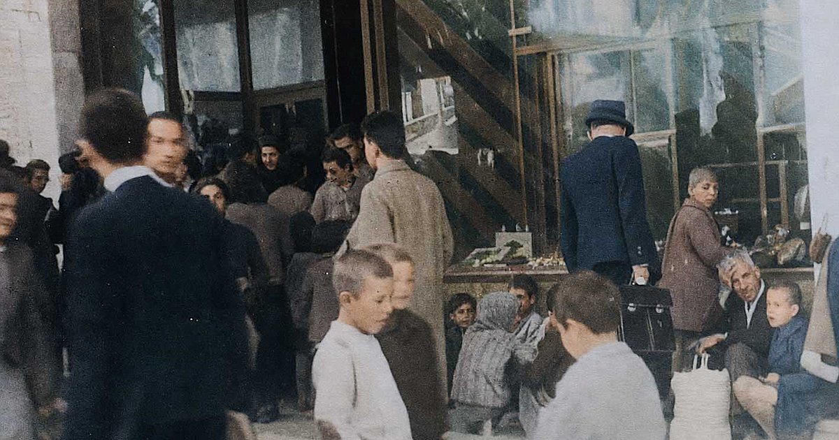 Στην οδό Πανεπιστημίου, μπροστά στο ζαχαροπλαστείο του Τσίτα. Οι μεγάλοι περιμένουν το συσσίτιο, τα παιδιά συμπαραστέκονται και συζητούν.