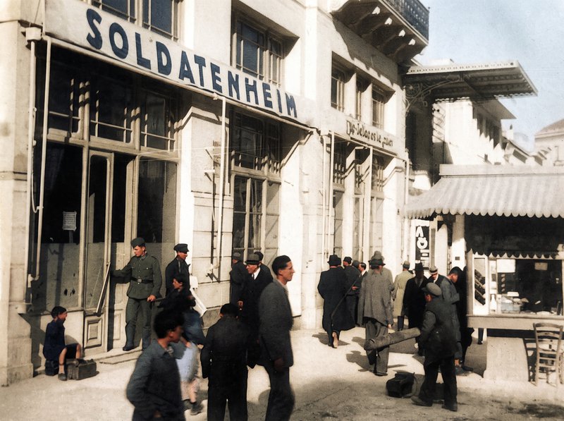 Το τότε καφενείο «Πανελλήνιον» στη γωνία Πανεπιστημίου και Εμμ. Μπενάκη επιτάχθηκε κατά την Κατοχή από τους Γερμανούς και έχει μετατραπεί σε «Σπίτι του Στρατιώτη». Πολλά τοπόσημα της πόλης εκείνη την εποχή ανανοηματοδοτήθηκαν.